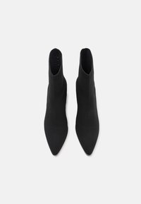 Černé špičaté kotníkové boty s pleteným svrškem, s přiléhavým designem a žebrovanými okraji, vyrobené z hladkého, elastického textilu.