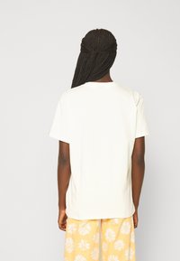 Weißes Baumwoll-T-Shirt mit kurzen Ärmeln, Rundhalsausschnitt und lockerer Passform, von hinten gezeigt. Glatte Textur, einfaches Design.