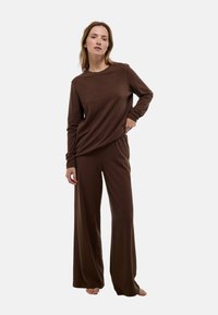 Haut à manches longues marron et pantalon large assorti en tissu doux. La tenue présente une coupe décontractée et une taille élastique.