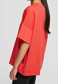 Rød oversized t-shirt lavet af bomuld, med korte ærmer og rund halsudskæring. Mærket er synligt i kanten.