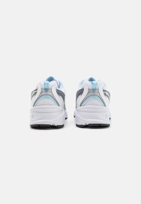 Weiße und hellblaue Sportschuhe mit Obermaterial aus Mesh, grauen Akzenten, gepolstertem Kragen und dämpfenden Sohlen. Sichtbare schwarze Gummisohle.
