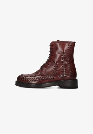 Botas de cuero hasta el tobillo en burdeos con intrincados detalles trenzados, cordones en la parte frontal y un tacón apilado. Textura suave y forma estructurada.