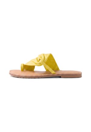 Sandalia amarilla tipo slip-on con nudo, suela plana color cuero, tira ancha de tela y puntera abierta, mostrada de perfil sobre fondo blanco.