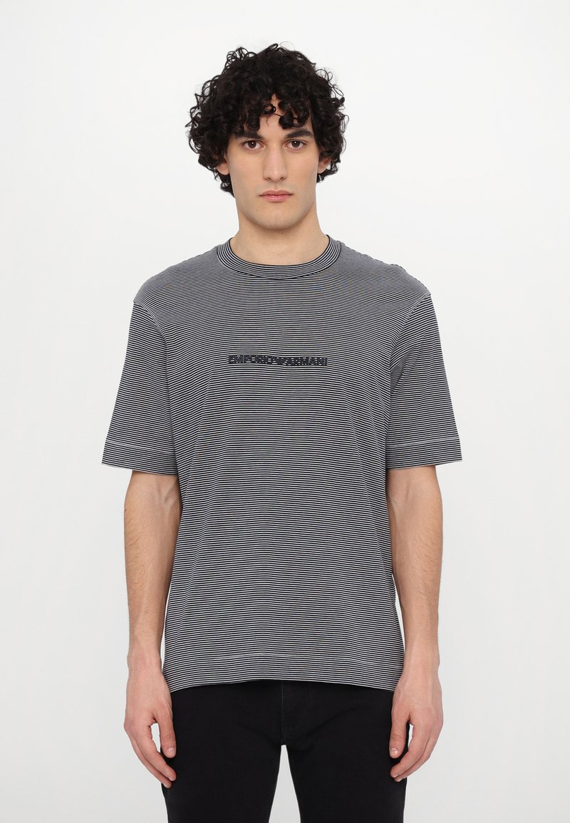 T-shirt de manga curta riscada em cinza e branco, com gola redonda e logótipo bordado "Emporio Armani" no peito. Tecido macio.