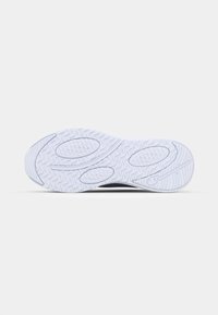Shoe sole with a textured white rubber surface, featuring wavy patterns and oval grips for traction; brand logo embossed near the heel.