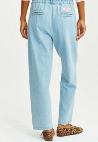 Svetlo modré, elastické džínsy s voľným strihom a elastickým pásom. Obsahujú dve zadné vrecká a ružovú nášivku s logom.