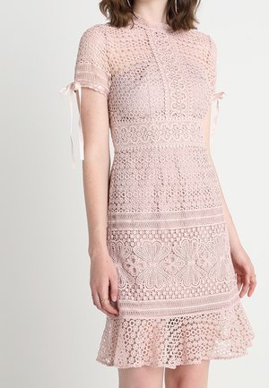 Vestido de encaje rosa claro con mangas cortas, que presenta patrones intrincados, un corsé ajustado y un dobladillo acampanado. Se ata en los hombros.