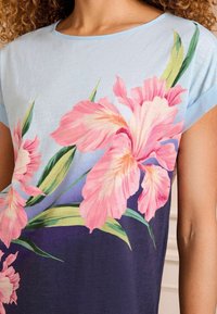 Trumpas rankovės marškinėliai, pagaminti iš šviesiai mėlynos medžiagos, su dideliu rožiniu gėlių raštu ir spalvos pereinamuoju efektu nuo mėlynos iki tamsiai violetinės. Lygi tekstūra.