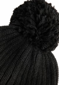 Schwarze gestrickte Mütze mit vertikalem Rippenmuster und einem flauschigen Bommel oben, aus weichem, strukturiertem Stoff.