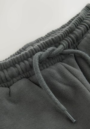 Hallid dressipüksid elastse vöökoha ja nööriga. Materjal tundub pehme, sileda tekstuuriga ja peente õmblustega.