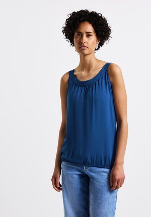 Blauw mouwloos topje van zachte stof met een gerimpelde halslijn en elastische onderkant, gecombineerd met lichtblauwe denimshorts.