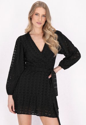 Schwarzes Wickelkleid mit langen puffärmel, das ausgeschnittene florale Muster, eine Bindegürtel und einen geschichteten Rüschensaum aufweist. Hergestellt aus atmungsaktivem Material.