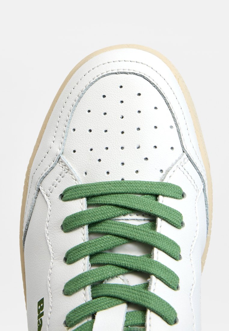 Białe skórzane sneakersy z perforowanym noskiem, zielonymi sznurowadłami i beżową gumową podeszwą. Posiadają akcenty z przeszyciami oraz logo na boku.