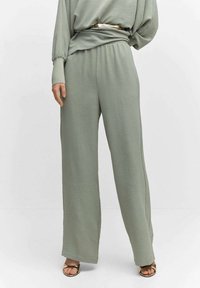 Pantalons larges vert-gris clair en tissu texturé, avec une taille élastique et un haut surdimensionné bien rentré à manches longues.