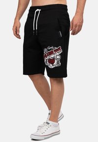 Zwarte katoen shorts met een elastische tailleband, witte trekkoord, zijzakken en een kleurrijk grafisch ontwerp met schedels en tekst.