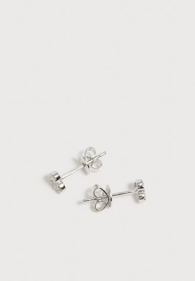 Paire de boucles d'oreilles en argent avec fermoir papillon sur un fond blanc uni.