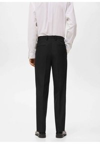 Zwarte op maat gemaakte broek met een rechte snit, voorzien van twee achterzakken en een gladde stoftextuur. Draagt een licht gestreept shirt.