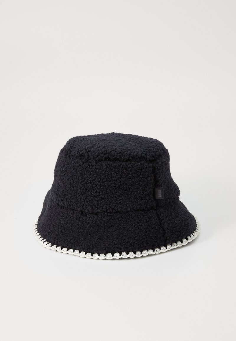 Svart fleece-bøttehatt med teksturert overflate, med hvit scalloped pynt langs kanten og en subtil logo på siden.