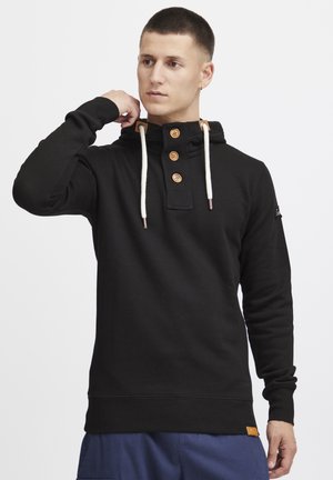 Schwarzer Kapuzenpullover aus Baumwolle mit einer Knopfleiste mit Holzknöpfen, kontrastierenden beige Akzenten und Kordelzugdetails.