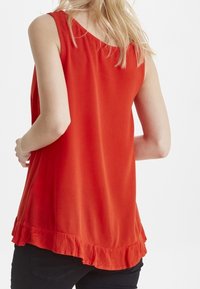 Top rosso senza maniche realizzato in tessuto leggero, con scollatura rotonda e orlo arricciato. Nessun motivo o dettaglio hardware visibile.