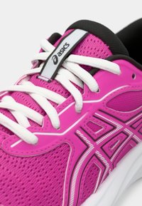 Κοντινό πλάνο ενός ροζ αθλητικού παπουτσιού ASICS με λευκές κορδόνες και μαύρη επένδυση, που δείχνει υλικό διχτυού και το λογότυπο της μάρκας στη γλώσσα του.