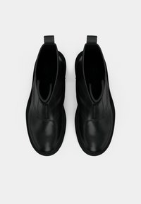Paire de bottines en cuir noir avec fermeture éclair à l'avant et languettes, vues de dessus sur fond blanc.