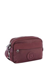 Burgundská nylonová taška přes rameno se zipovým uzávěrem, embosovaným logem a textilním popruhem. Má kompaktní obdélníkový tvar a stříbrné kování.
