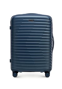 Valigia rigida blu navy con righe orizzontali, chiusura con zip, maniglia superiore e quattro ruote nere per una facile mobilità. Logo del marchio esposto in modo prominente.