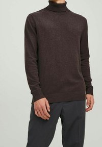 Pull marron à col roulé et manches longues en tissu tricoté texturé ; ajusté au niveau du col et des poignets avec une couleur unie sur l'ensemble.