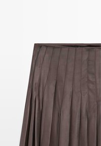 Mörkbrun plisserad kjol med vertikala sömmar och ett brett midjeband på en vit bakgrund.