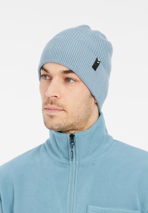 Bonnet en tricot côtelé bleu clair avec une petite étiquette noire. Texture douce, design ajusté, adapté pour une tenue décontractée ou des activités de plein air.