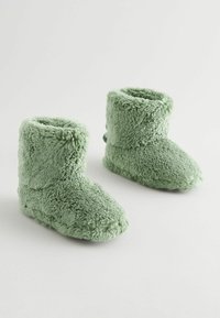 Grüne, flauschige, weich strukturierte Stiefel mit einer kurzen Knöchelhöhe und einem runden Zehendesign. Ein fleeceartiges Material bedeckt die gesamte Oberfläche.