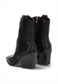 Botines de cuero negro con tacón ancho, con patrones florales en relieve y cierre de cremallera en la parte trasera. Textura lisa.