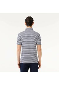 Marinblå och vit randig kortärmad polotröja med krage, som har en slim fit och mjukt bomullstyg. Minimalistisk design, utan logotyper.