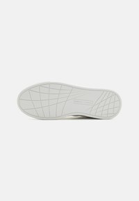 Suola di sneaker in gomma bianca con un motivo testurizzato, caratterizzata da un sottile design a griglia e branding al centro. Finitura liscia complessiva.