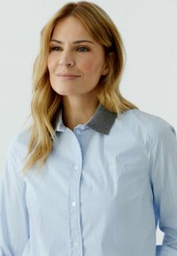 Hellblau gestreiftes Hemd mit grauem Kragen. Verfügt über eine Knopfverschluss und dezente Logo-Stickerei auf der Brust. Glatte Stoffstruktur.