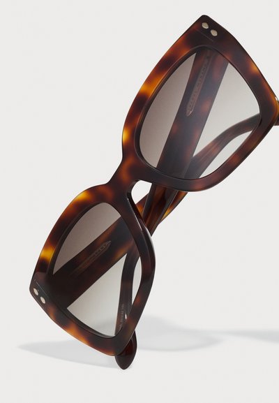 Occhiali da sole tartaruga con montatura quadrata oversize, lenti grigie sfumate e finitura lucida liscia. Presentano piccoli dettagli in metallo.