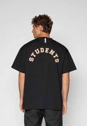 T-shirt nera in cotone con la scritta "STUDENTI" in lettere arancioni arcuate sulla schiena. Vestibilità rilassata con maniche corte e design a girocollo.