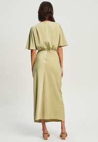 Olivengrünes Midikleid mit kurzen, ausgestellten Ärmeln, tailliertem Bund und glatter, glänzender Textur; verfügt über einen Rückenschluss und einen seitlichen Schlitz.