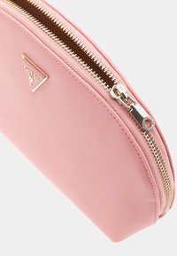 Borsetta cosmetica rosa, con texture, dotata di una cerniera dorata e di un tocco metallico con logo. Finitura liscia, forma arrotondata, adatta per contenere oggetti personali.