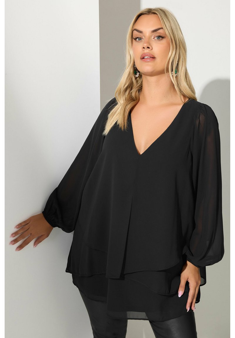 Svart, lätt blus med V-ringning, flödande långa ärmar, lagerdesign och mjuk textur. Lämplig för både vardags- och formella tillfällen.