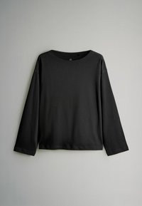 Maglietta nera a maniche lunghe realizzata in tessuto morbido, con scollatura rotonda e vestibilità comoda, caratterizzata da una texture liscia e senza pattern o accenti visibili.
