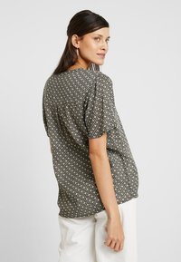 T-shirt à manches courtes avec un motif géométrique noir et blanc, fabriqué en tissu léger, avec une coupe décontractée et un col rond.