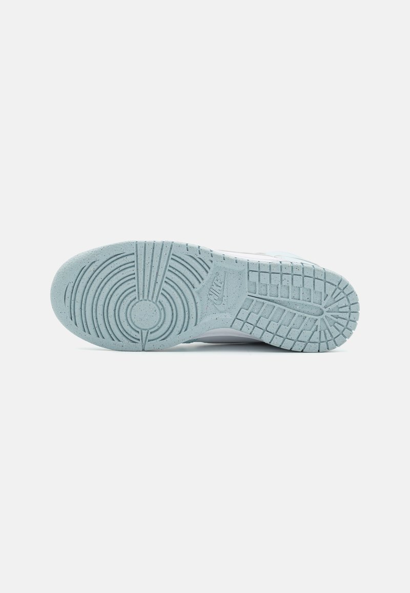 Suola di sneaker in gomma di un blu chiaro, con pattern di grip testurizzati, emblema circolare e speckle incorporati per una trazione e aderenza migliorate.