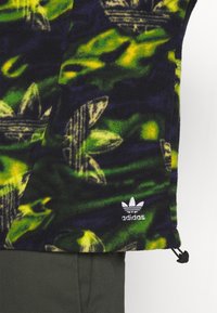 Pullover in pile di colore nero, verde e giallo con motivi astratti di foglie; presenta un logo Adidas e un cordino regolabile all'orlo.