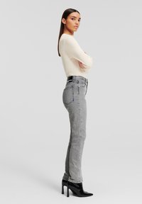 Höga grå jeans med rak ben, tillverkade av denim, och med en svart midjebandsetikett och femfickorsdesign.