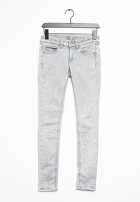Jeans ajustados de color gris claro, confeccionados en denim, con una cintura baja, cinco bolsillos y una sutil textura desgastada. Disponibles en una percha.