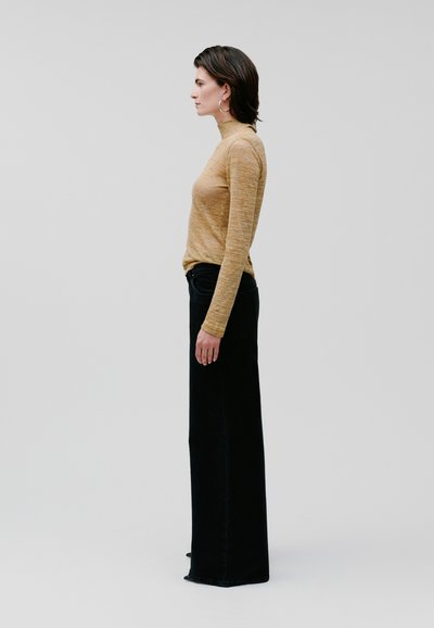 Yellow long-sleeve turtleneck top paired with high-waisted black wide-leg jeans. Smooth texture, minimal design, no visible patterns or hardware.