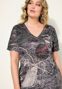 Camiseta de cuello en V negra y gris con arte lineal abstracto en blanco y un detalle de corazón rojo brillante, fabricada en una suave tela texturizada.