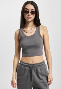 Sivi rebrasti crop top sa širokim trakama, uparen sa sivim trenirkama koje imaju elastičnu struk i izvezeni logo detalj.